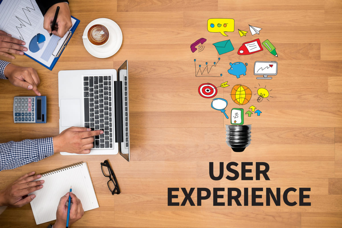 A business team working at a desk with the word “user experience” and drawn icons.