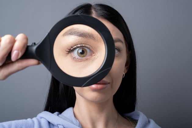 A woman with a magnifying glass around her eye