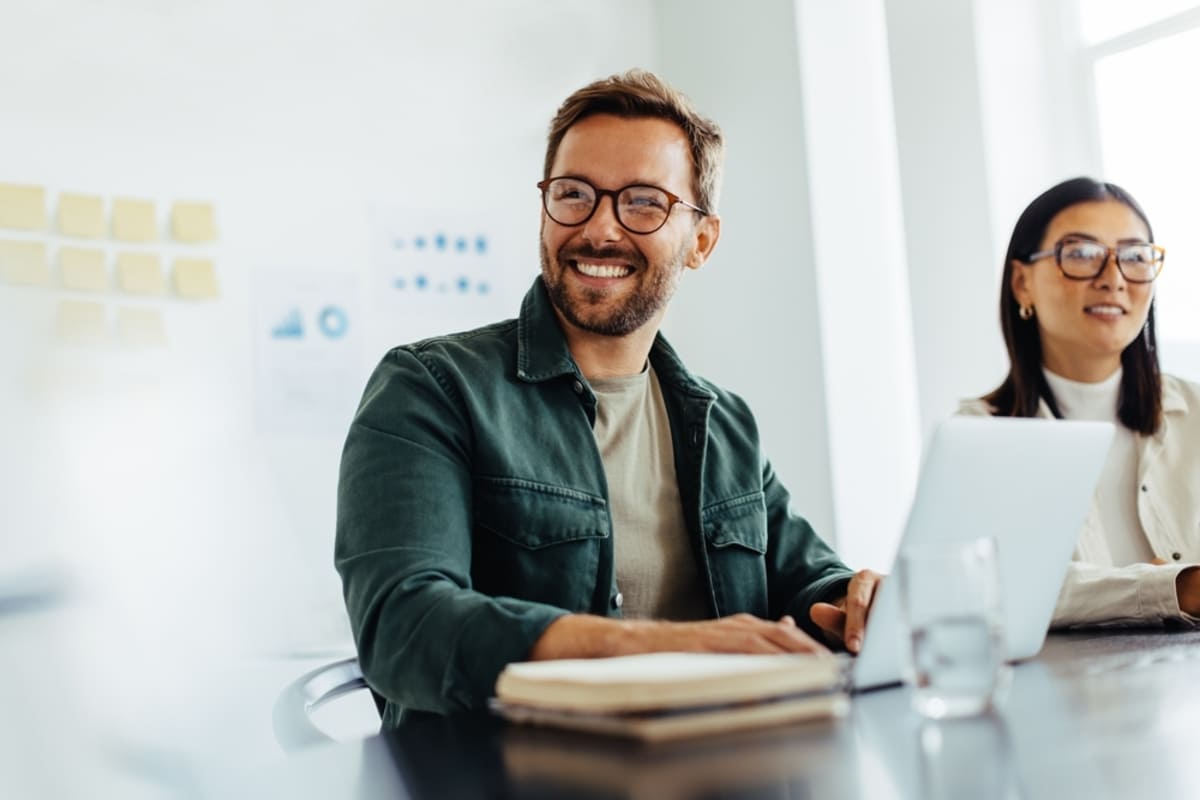 A man smiling at his laptop in an office space