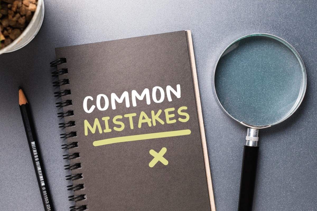 A notebook that says common mistakes next to a magnifying glass and a pencil