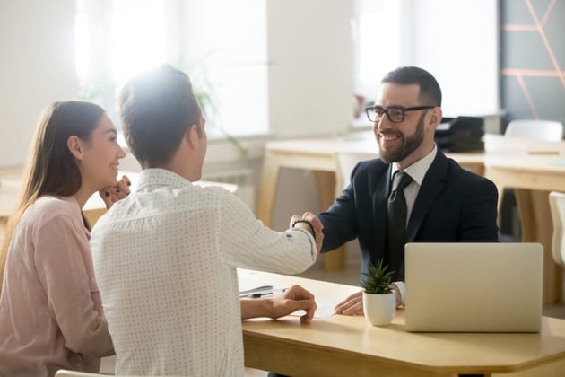 Two people discussing with a businessman and shaking hands.